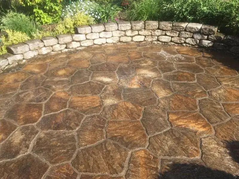 Runde Natursteinterrasse mit Granit-Mauerrand, dunkel und feucht verschmutzt